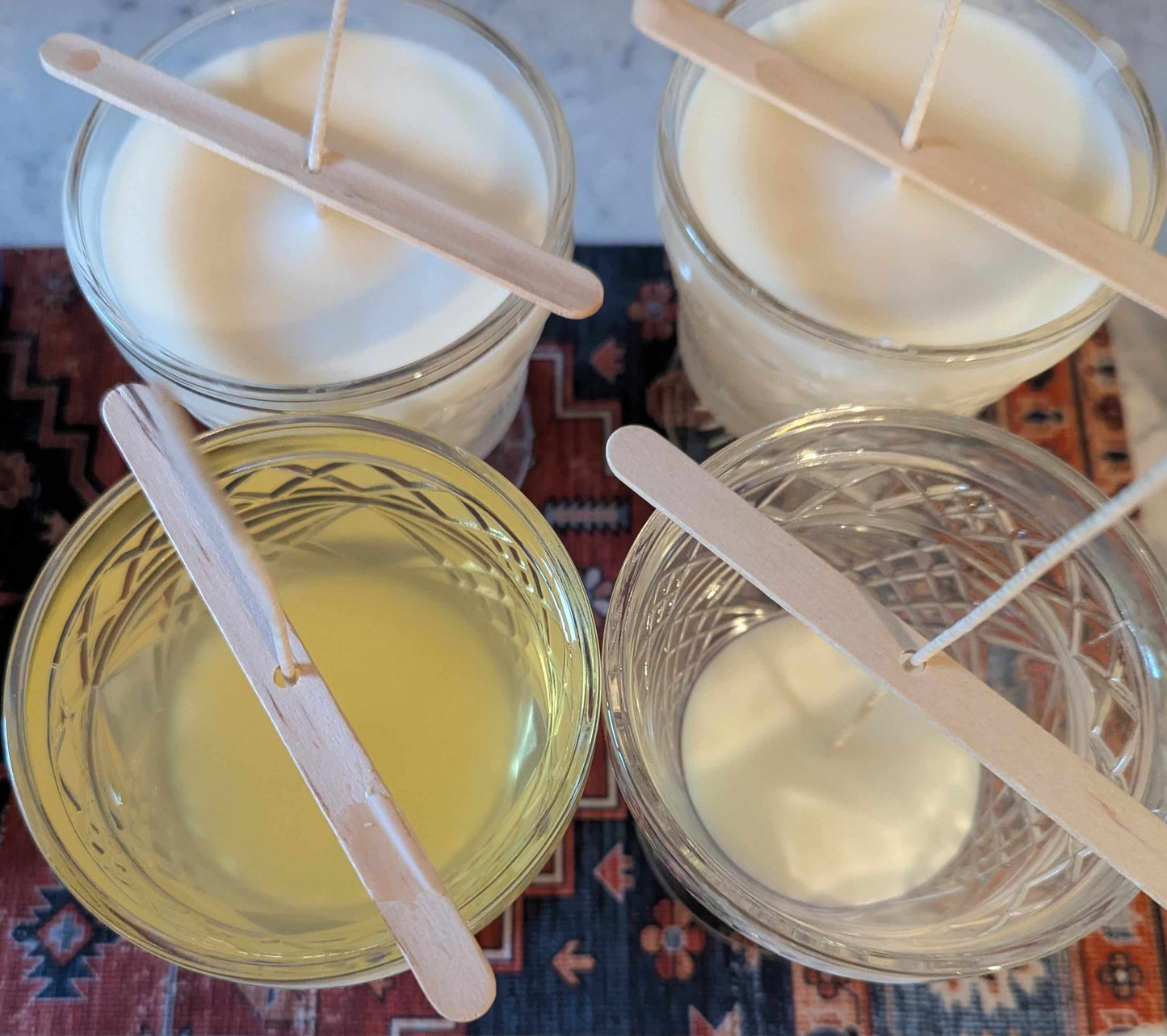 Hand poured coco-soy wax candles cooling in glass jars with wooden wicks, showcasing a small batch candle-making process.