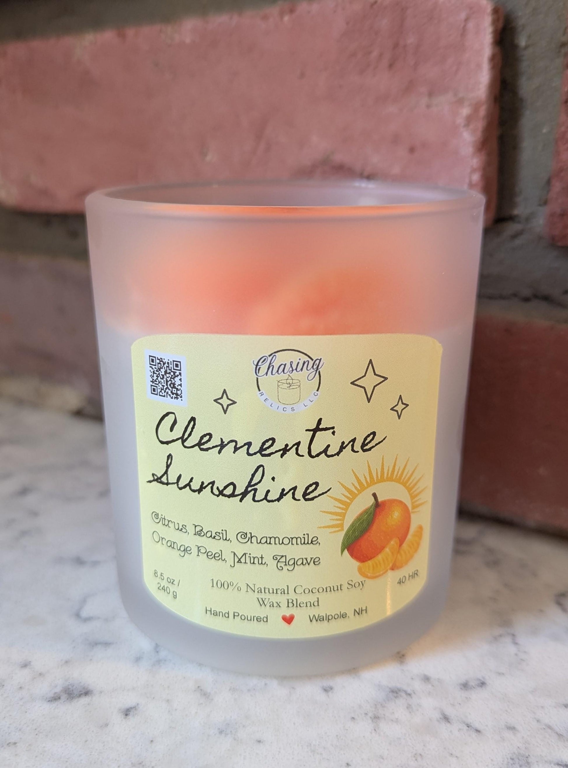 Hand-poured Clementine Sunshine candle with citrus slice wax top, made from 100% natural coconut soy wax, displayed on a marble surface.