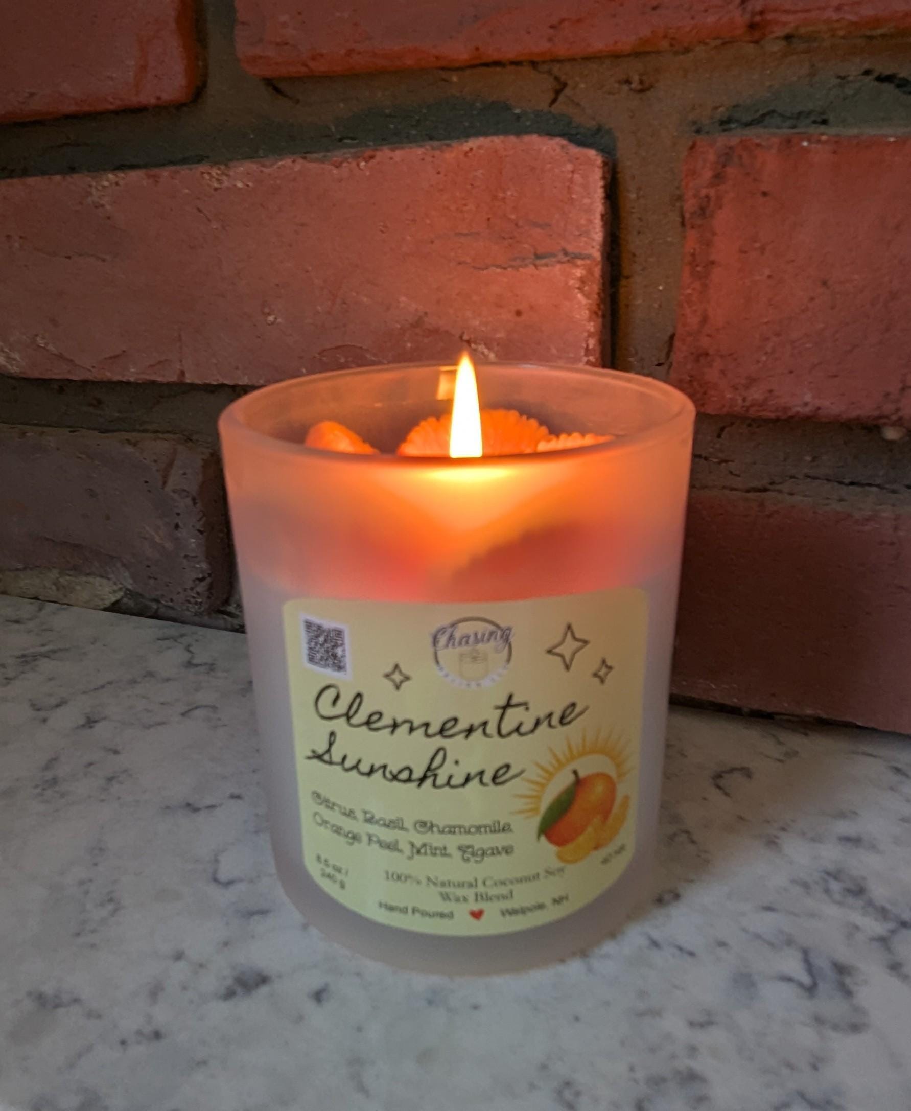 Hand-poured Clementine Sunshine candle with citrus slice wax top, made from 100% natural coconut soy wax, displayed on a marble surface.
